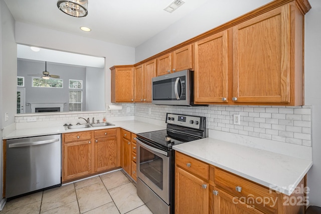 kitchen with brown cabinets, stainless steel appliances, light countertops, visible vents, and a sink