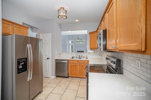 kitchen featuring appliances with stainless steel finishes, brown cabinets, light countertops, and a sink