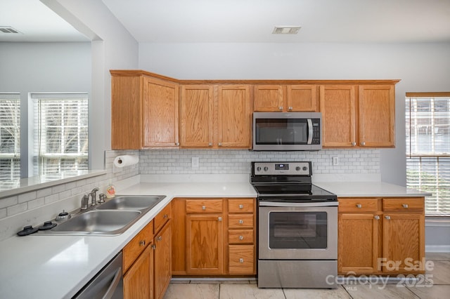 kitchen featuring appliances with stainless steel finishes, light countertops, and a sink