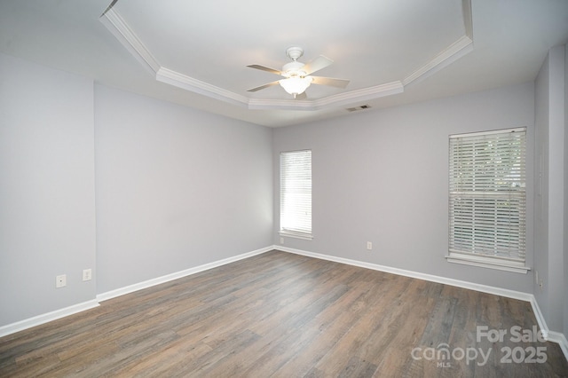 unfurnished room featuring dark wood-style floors, ceiling fan, a tray ceiling, and crown molding