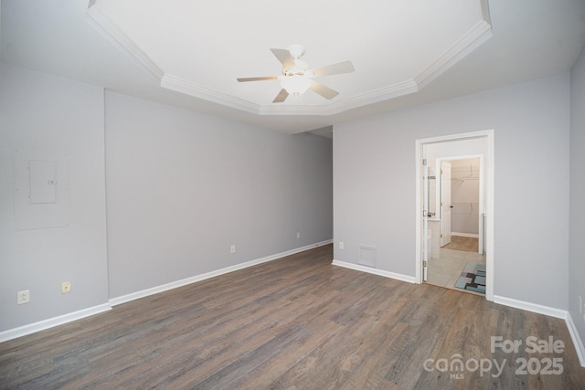 unfurnished bedroom with a tray ceiling, dark wood-style flooring, crown molding, and baseboards