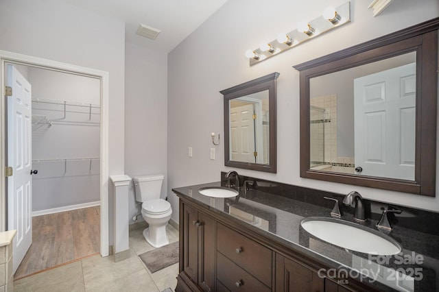 bathroom featuring visible vents, a sink, toilet, and double vanity