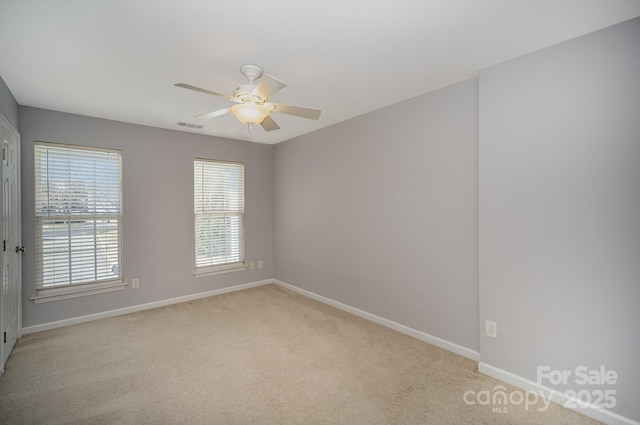 spare room featuring light carpet, ceiling fan, visible vents, and baseboards