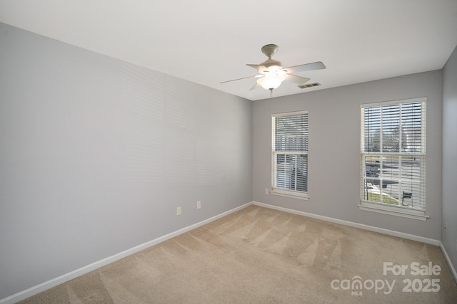 spare room with baseboards, a ceiling fan, visible vents, and light colored carpet