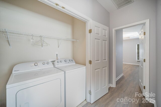 washroom with laundry area, light wood finished floors, baseboards, visible vents, and washer and clothes dryer