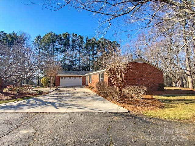 ranch-style home featuring a garage, concrete driveway, and brick siding