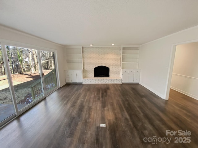 unfurnished living room with baseboards, built in features, ornamental molding, a brick fireplace, and dark wood-style floors