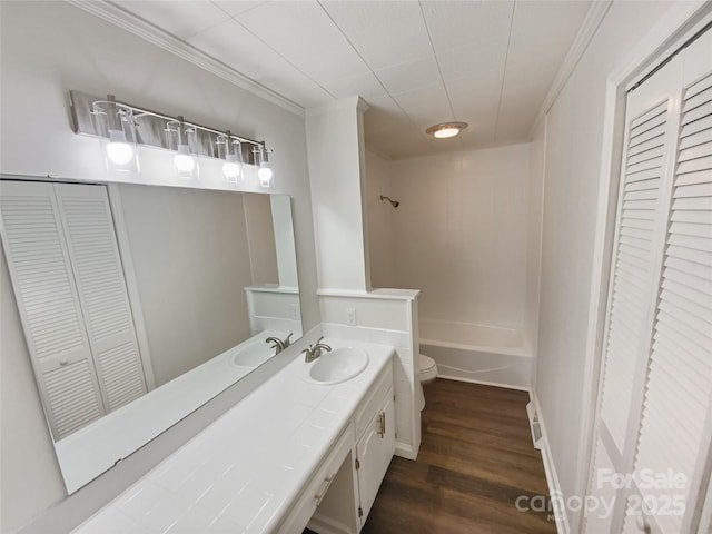 bathroom featuring toilet, ornamental molding, wood finished floors, vanity, and a closet