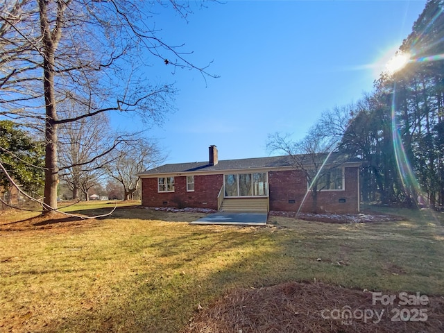 rear view of property featuring a lawn, a chimney, crawl space, a patio area, and brick siding