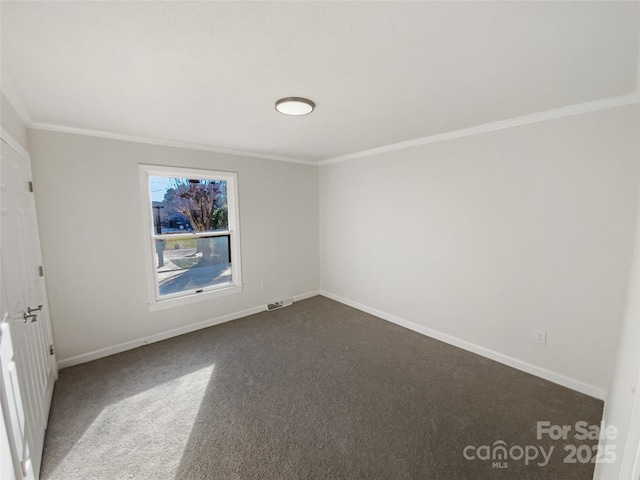 spare room with visible vents, baseboards, dark colored carpet, and crown molding