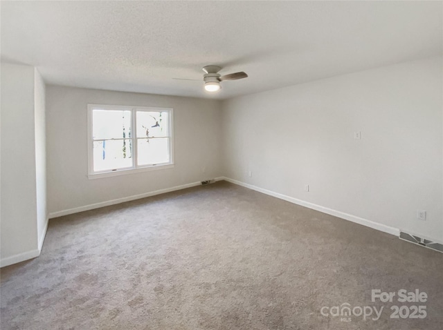 carpeted spare room featuring visible vents, ceiling fan, a textured ceiling, and baseboards