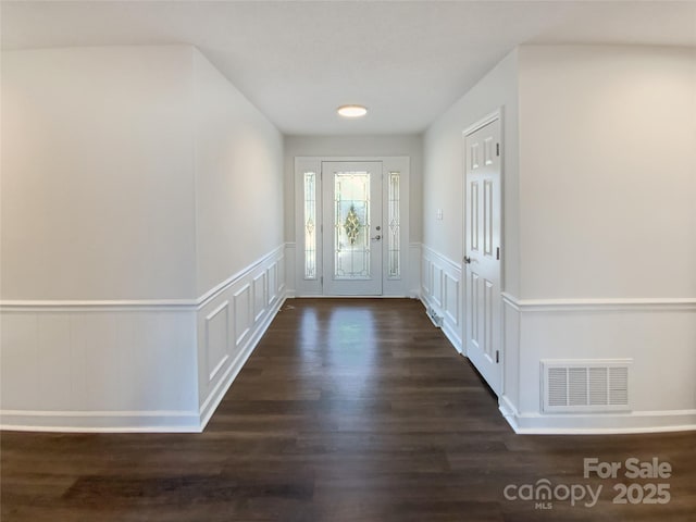 entryway with a wainscoted wall, visible vents, a decorative wall, and dark wood-type flooring