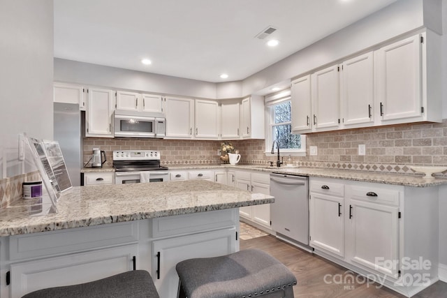 kitchen featuring stainless steel appliances, visible vents, and white cabinetry