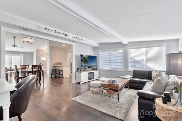 living area featuring visible vents, beamed ceiling, and wood finished floors