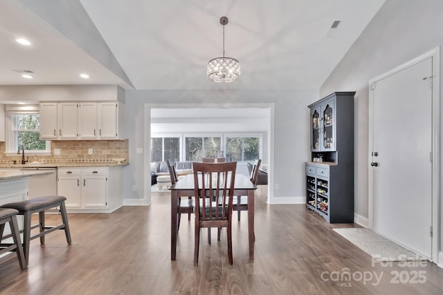 dining area with vaulted ceiling, wood finished floors, visible vents, and baseboards