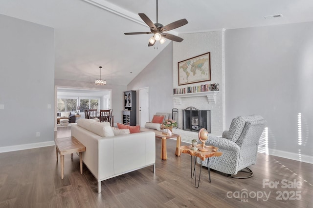 living area featuring high vaulted ceiling, a brick fireplace, baseboards, and wood finished floors