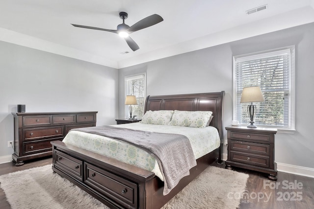 bedroom with dark wood-style floors, visible vents, ceiling fan, and baseboards