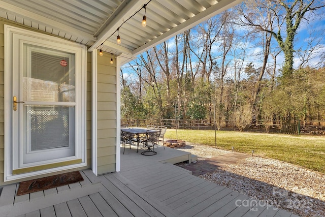 wooden deck with outdoor dining area, a fenced backyard, and a lawn