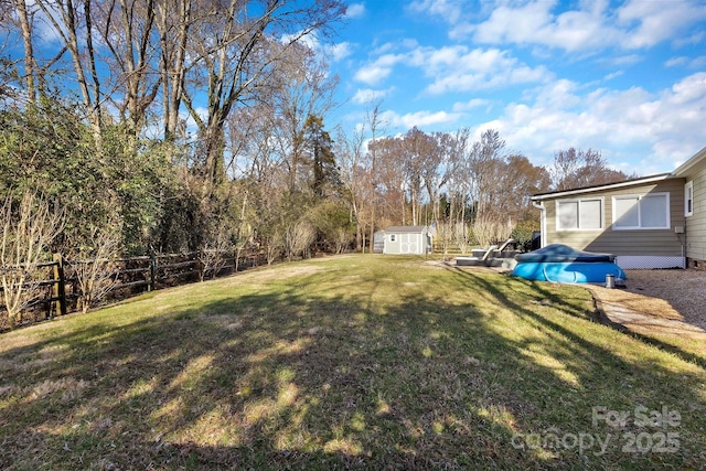 view of yard featuring a storage shed, fence, and an outdoor structure