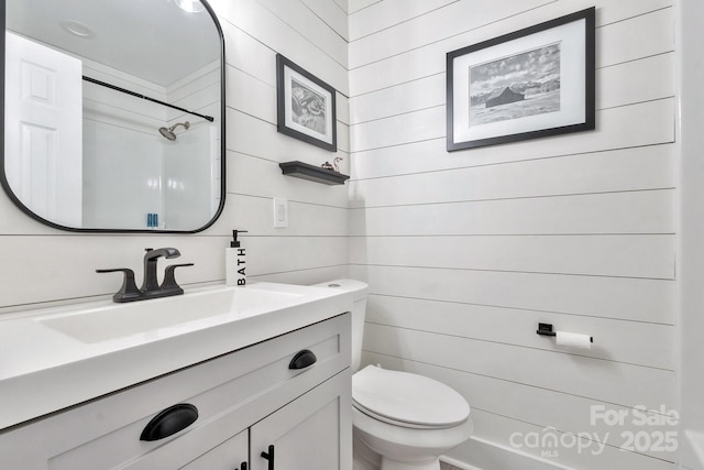 bathroom with walk in shower, vanity, and toilet