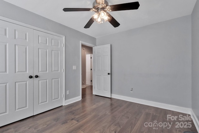 unfurnished bedroom with ceiling fan, dark wood-style flooring, a closet, and baseboards