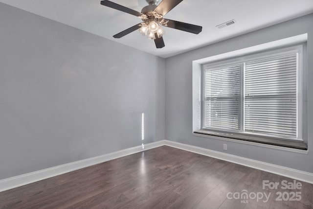 unfurnished room featuring visible vents, dark wood finished floors, baseboards, and ceiling fan