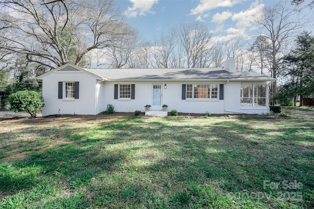 ranch-style home with a sunroom, a chimney, and a front lawn