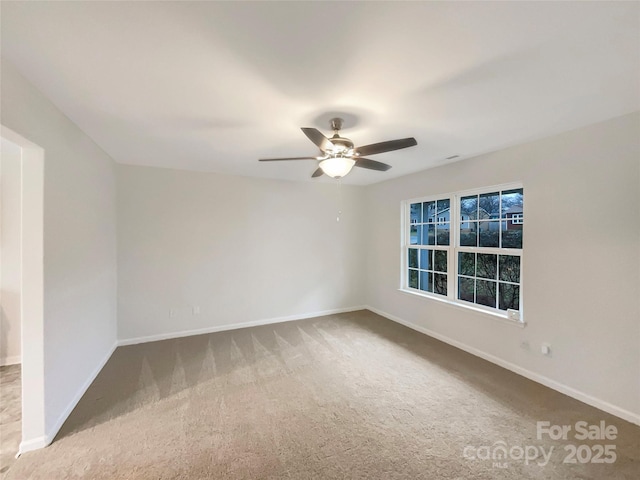 spare room with a ceiling fan, carpet flooring, and baseboards