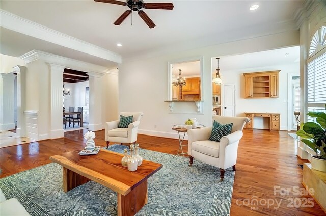 6548 Robin Hollow Dr, Mint Hill, NC 28227 - living room featuring wood finished floors, ceiling fan with notable chandelier, baseboards, and ornate columns