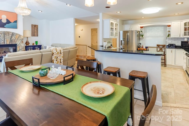 dining area with light tile patterned floors, a fireplace, a chandelier, and recessed lighting