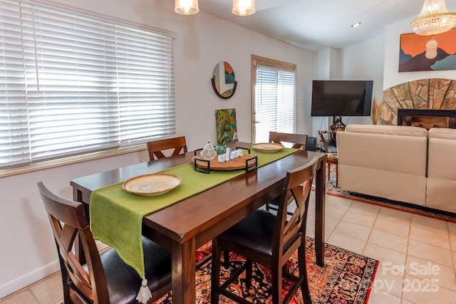 dining area with light tile patterned floors, a fireplace, and baseboards