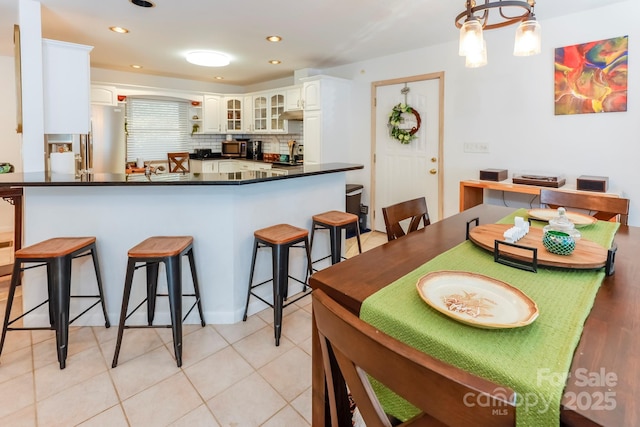 kitchen featuring dark countertops, white cabinets, a kitchen breakfast bar, and decorative backsplash