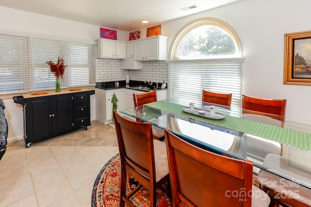 kitchen with light tile patterned floors, tasteful backsplash, visible vents, white cabinetry, and dark cabinets