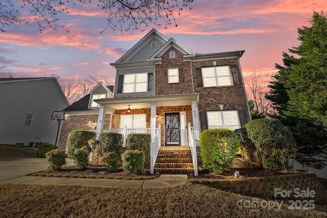 view of front of home featuring brick siding, covered porch, and driveway