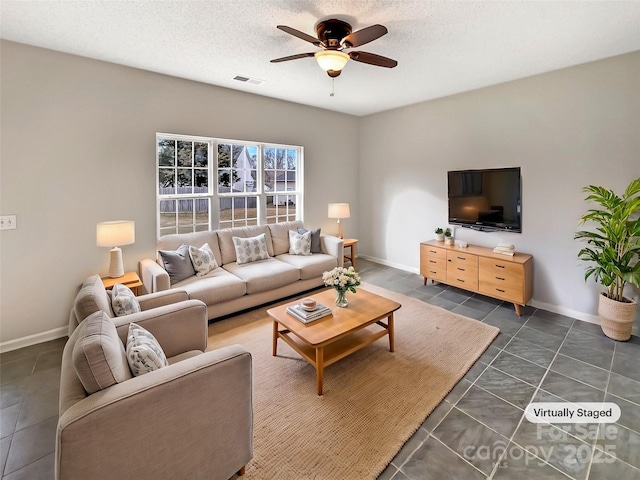 living room with a textured ceiling, dark tile patterned floors, visible vents, and a ceiling fan