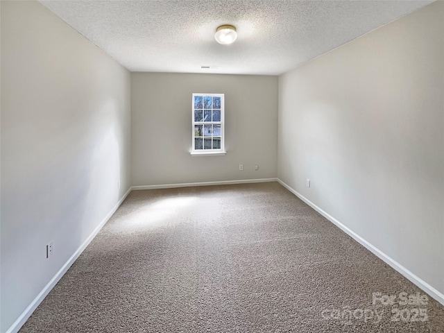 carpeted spare room featuring a textured ceiling, visible vents, and baseboards