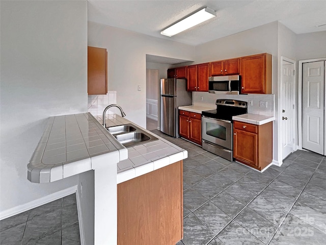 kitchen with stainless steel appliances, a peninsula, a sink, and a kitchen breakfast bar