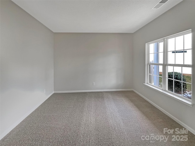 unfurnished room featuring carpet, visible vents, and baseboards