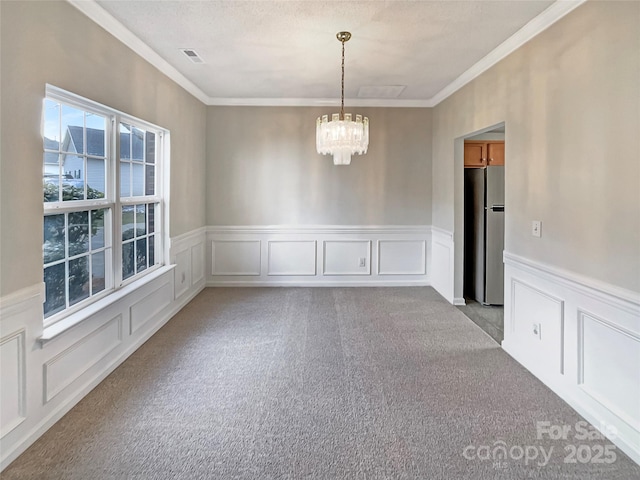 spare room with visible vents, light colored carpet, crown molding, a chandelier, and a decorative wall