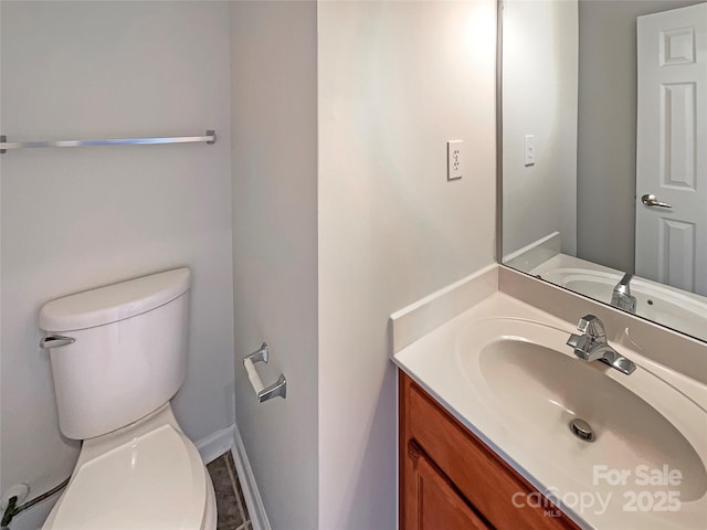 bathroom featuring baseboards, vanity, and toilet