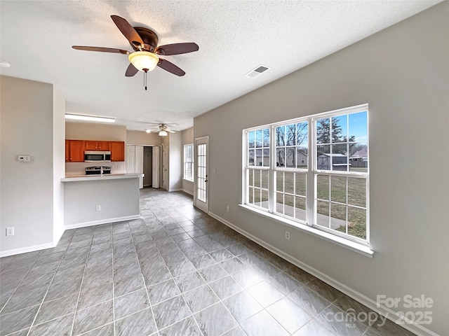 unfurnished living room with a ceiling fan, baseboards, visible vents, and a textured ceiling