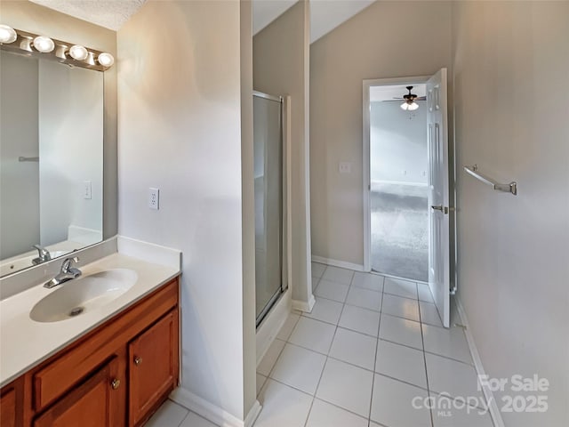 bathroom featuring lofted ceiling, tile patterned flooring, a shower stall, and vanity