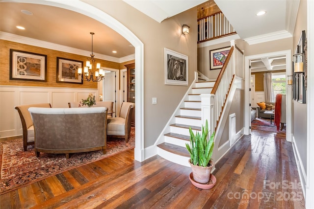 stairs featuring an inviting chandelier, hardwood / wood-style flooring, a decorative wall, and ornamental molding