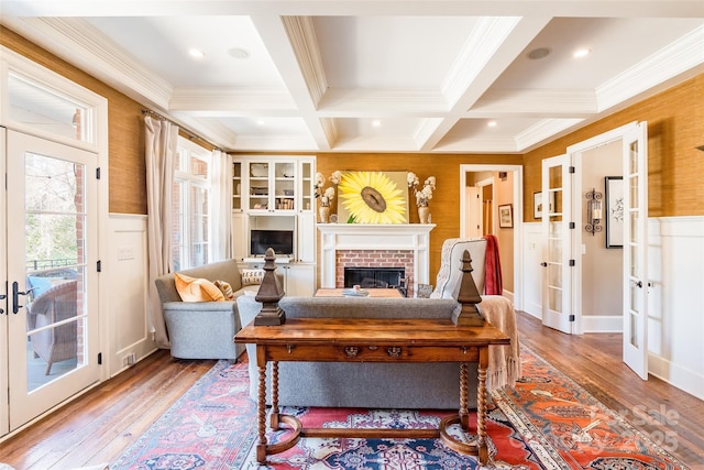 living room featuring beam ceiling, hardwood / wood-style flooring, coffered ceiling, french doors, and a fireplace