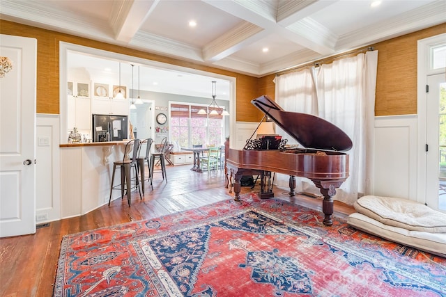 living area featuring beamed ceiling, wainscoting, coffered ceiling, and hardwood / wood-style floors