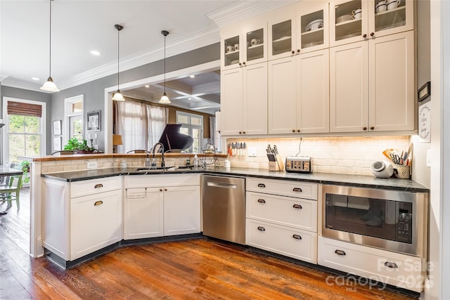 kitchen featuring backsplash, built in microwave, a peninsula, dark wood-style floors, and stainless steel dishwasher