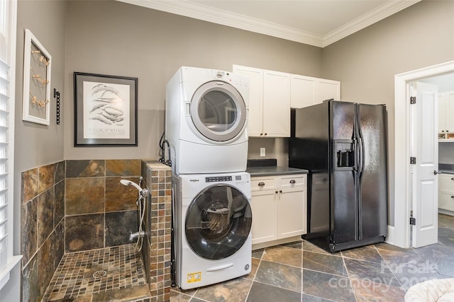 washroom with crown molding, cabinet space, stacked washer / drying machine, and stone finish flooring