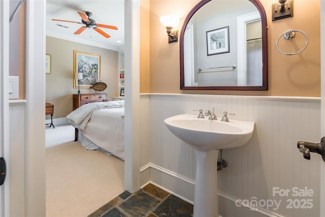 bathroom with visible vents, a wainscoted wall, ornamental molding, stone finish floor, and a ceiling fan