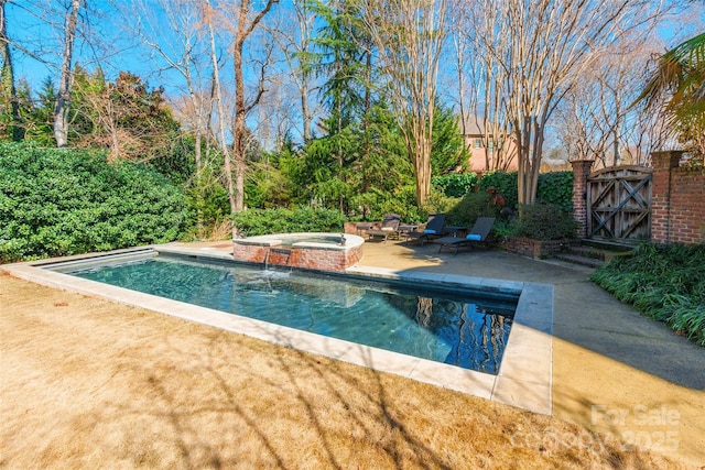 view of swimming pool with a patio, a pool with connected hot tub, and a gate