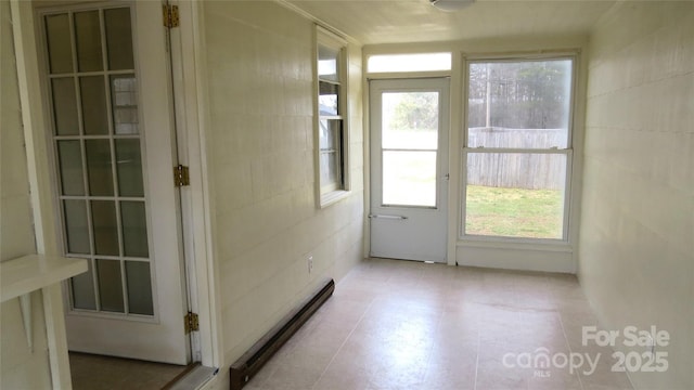 unfurnished sunroom with a baseboard heating unit